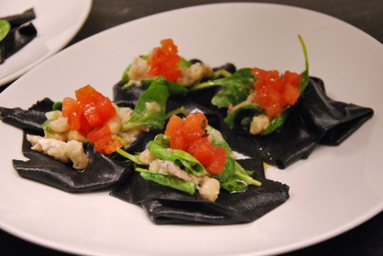 Raviolo nero aperto ripieno di insalatina di cicale di mare, pomodori e spinacetti